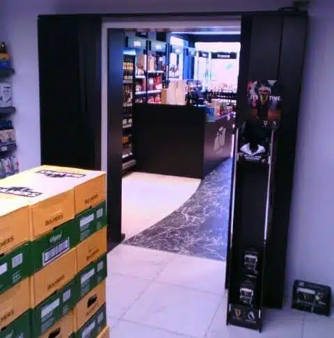 AirDoor Curve installation at Hanlon's Gala showing doorless entrance to walk-in beer fridge with customer access and product display