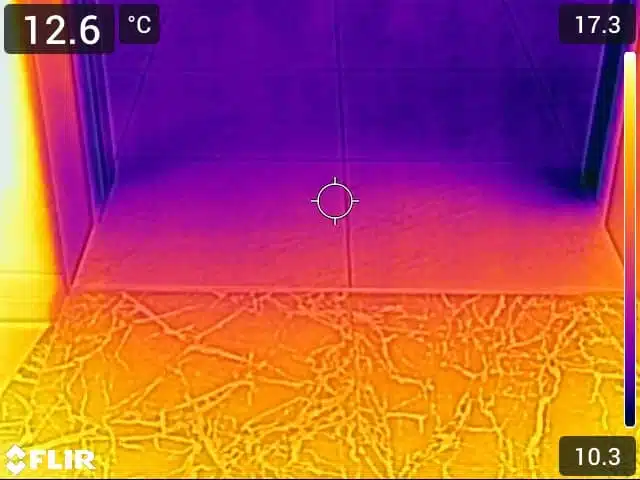 FLIR thermal imaging showing AirDoor Curve air barrier at the doorway with temperature gradient from 12.6°C warm air outside to 10.3°C cold air inside